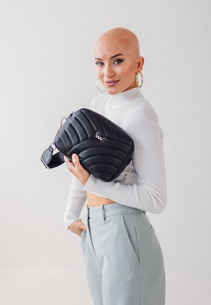 Prošívaná černá crossbody taška se stříbrným logem, obsahující řetízkový popruh a obdélníkový tvar. Hladká, umělá kůže.