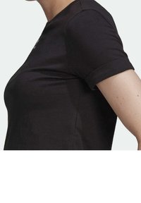 Svart bomulls T-shirt med rund hals och korta uppvikta ärmar, med en mjuk textur och minimalistisk design.