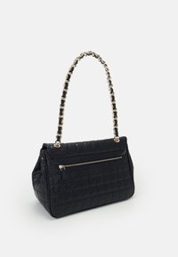 Musta tilkuilla vuorattu käsilaukku, valmistettu synteettisestä materiaalista, jossa on kultaketjuolkaimet ja etupuolen vetoketjullinen tasku. Sujuva pinta, jossa on kohokuvioitu kuvio.