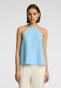 Top azzurro chiaro senza maniche con collo all'americana, caratterizzato da righe diagonali texturizzate e orli grezzi, abbinato a pantaloni color crema.