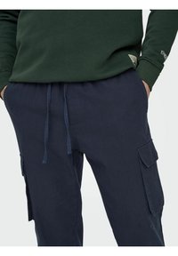 Pantaloni cargo blu navy con vita regolabile, tasche laterali e vestibilità comoda. Il materiale sembra morbido con una texture liscia e dettagli minimi.