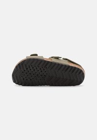 Lätt sandal med en korkfotbädd, gröna remmar och en texturerad svart gummisula som har ett zigzagmönster för bättre grepp.