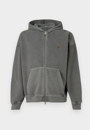 Siva zip-up kapuca izdelana iz mehke tkanine. Ima kenguru žep in majhen logo na levem prsnem delu. Zaključena je s kapuco s vrvico.