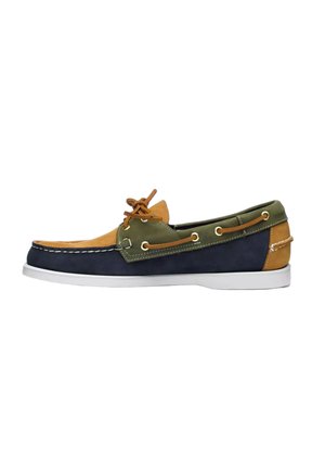 Chaussure bateau multicolore en cuir pour homme avec des panneaux bleus, verts et beige, semelle blanche et lacet en cuir noué sur le dessus.