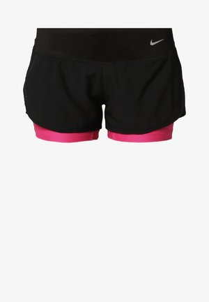 Femme portant un débardeur noir Nike, un short noir avec un sous-short rose et des baskets Nike noires, marchant vers l'avant sur un fond uni.