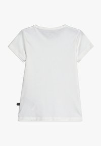 Bijela majica kratkih rukava s okruglim izrezom, glatke teksture i prošivenim rubovima. Na boku ima malu oznaku marke.