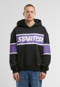 Black hoodie with purple and white horizontal stripes. Features a large "STARTER" logo, a front pocket, and a drawstring hood.
