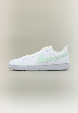 White low-top sneaker with light green Nike swoosh, white laces, and speckled gray sole on a plain neutral background.