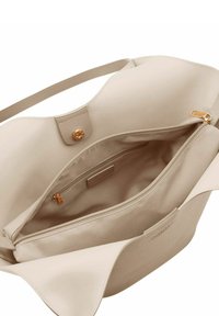 Sac fourre-tout beige à texture lisse, doté d'une fermeture à pression dorée, d'une poche intérieure zippée et d'un design minimaliste.