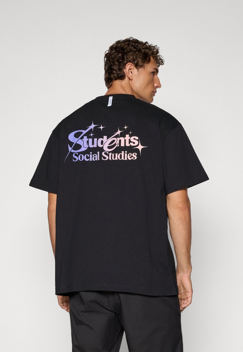 Svart bomulls t-skjorte med et stort flerfarget grafikk på baksiden som sier "Studenter Samfunnsfag" med stjerneakenter.