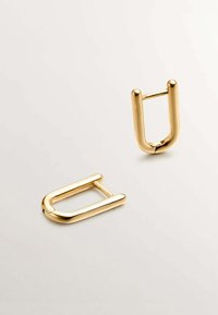 Hebilla en forma de U de metal dorado con un acabado liso y pulido. Presenta bordes redondeados y un diseño sencillo. Se muestran dos piezas.