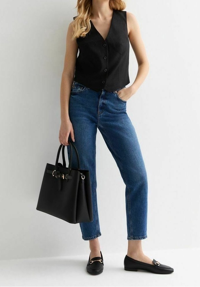 Svart ärmlös väst med knappar, blå raka jeans, svart handväska och svarta loafers med gulddetaljer. Släta texturer genomgående.