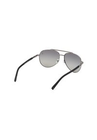 Gafas de sol estilo aviador con marco de metal plateado, lentes de gradiente gris y varillas de plástico negro. Cuenta con almohadillas nasales ajustables.