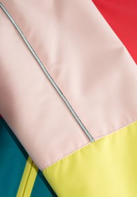 Flerfärgad vindjacka med paneler i rosa, röd, turkos och gul. Slätt, lättviktigt tyg med kontrasterande sömdetaljer.