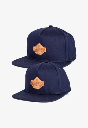 Granatowy czapka snapback wykonana z materiału, z łatą w skórze w kolorze brązowym oznaczoną napisem "BLACKSKIES PREMIUM SUPPLIES". Strukturalna korona, płaski daszek.
