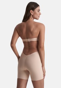 Beige shapewear shorts met een gladde textuur, hoge taille en een lage achterkant. Voorzien van een haak-en-oogsluiting op de achterkant.
