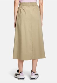 Beige middellange rok met een elastische tailleband, met een gladde textuur en een rechte snit, gecombineerd met stijlvolle sportschoenen.