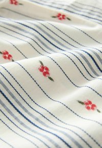 Baumwollstoff mit horizontalen blauen Streifen und kleinen roten Blumenmustern auf cremefarbenem Hintergrund, zeigt weiche Textur und Designdetails.