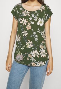 Groen bloemenprint top met korte mouwen, voorzien van een ronde halslijn, lichte stof, opvallende bloemen in roze en wit, en een afgeronde zoom.