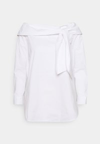 Blouse blanche en coton, à épaules dénudées, avec un détail noué à l'avant, manches longues et ourlet droit.