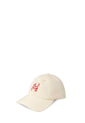 Beżowa czapka baseballowa z czerwonym, wyszywanym karykaturalnym psem na przednim panelu, prezentowana na białym tle.