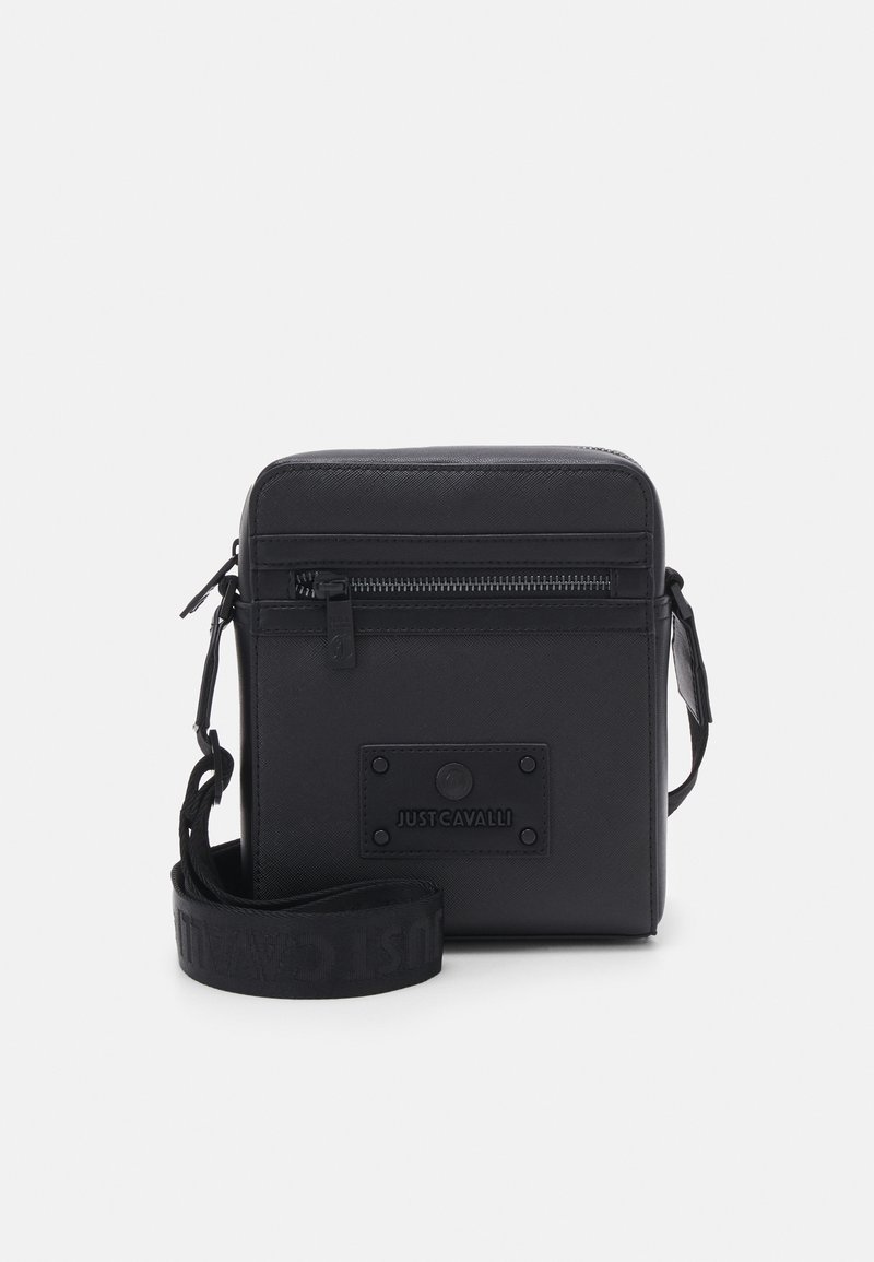 Czarna syntetyczna torba na ramię o kwadratowym kształcie, z zamkiem błyskawicznym, przednia kieszeń oraz pasek z logo z wytłoczonym tekstem.