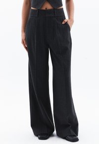 Pantaloni a gamba larga in tessuto grigio scuro con sottili righe verticali. Caratterizzati da vita alta e tasche laterali. Design strutturato e sartoriale.