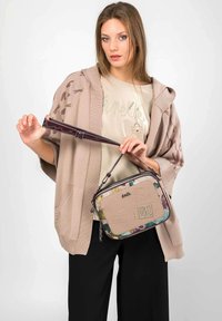 Pequeña bolsa rectangular en beige con patrones florales multicolores y diseño de logo; cuenta con una correa desmontable y un acabado suave y texturizado.