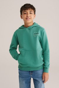 Grön huva gjord av mjukt tyg, med en känguruficka och ribbade ärmslut, samt en liten logotyp på bröstet.