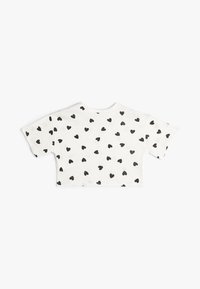 Afklippet hvid t-shirt med et helt mønster af små sorte hjerter. Korte ærmer, rund halsudskæring og glat bomuldsstruktur.