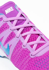 Fialová sportovní bota s síťovinou, kontrastním světle modrým akcentem a plochými tkaničkami. Obsahuje podrážku s vylepšenou přilnavostí a polstrovaný jazyk.