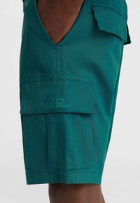 Shorts cargo teal en tissu léger, dotés d'une grande poche plaquée et d'un accent avec le logo O'Neill sur le côté gauche.