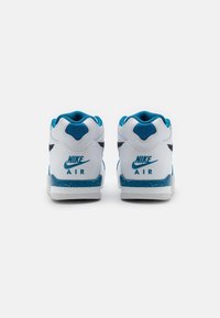 Pár bílých Nike Air tenisek s modrými akcenty, viděné zezadu na světlém jednobarevném pozadí.