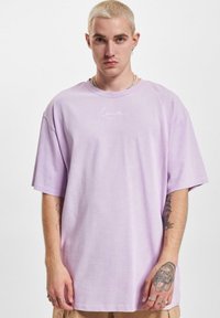 Light purple oversized T-shirt made of cotton, featuring subtle white embroidered logo on the chest and short sleeves.