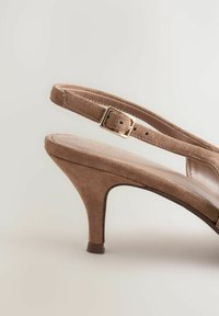Sandalía de tacón alto de ante beige con una correa y detalle de hebilla, que cuenta con un tacón afilado y una plantilla suave.