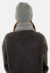 Gray ribbed knit beanie and matching scarf worn over a dark gray sweater, showcasing a soft texture and simple design.