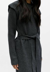 Abito lavorato a maglia grigio scuro con maniche lunghe a coste, spalline imbottite e una cintura annodata in vita, che presenta una struttura morbida e una vestibilità rilassata.