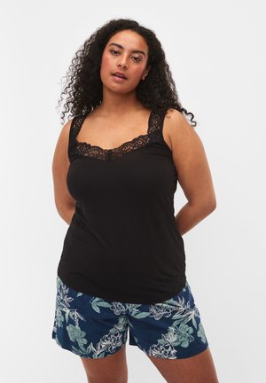 Schwarzes Tanktop mit Spitzenkante am Ausschnitt und den Trägern, kombiniert mit blauen Shorts im floralen Muster in Grüntönen und Marineblau.
