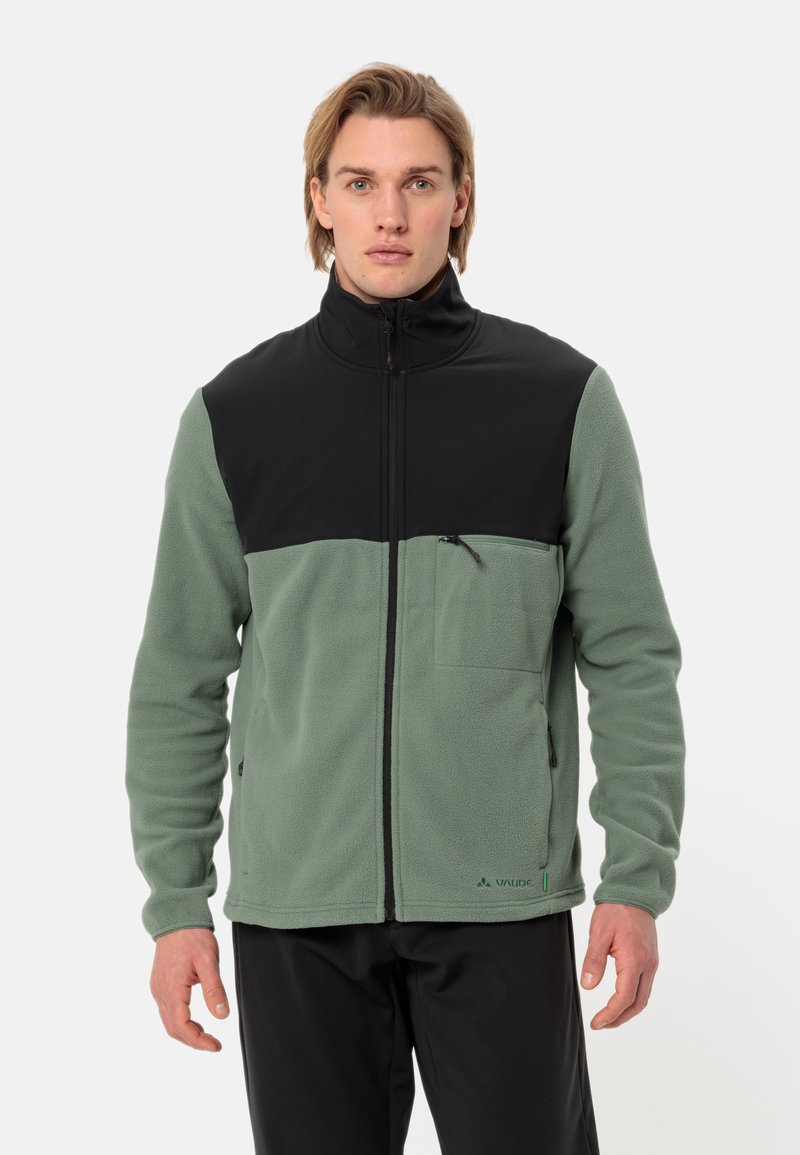 Giacca in pile con una sezione superiore nera e una sezione inferiore verde, dotata di una tasca con zip sul petto e un design con colletto alto.