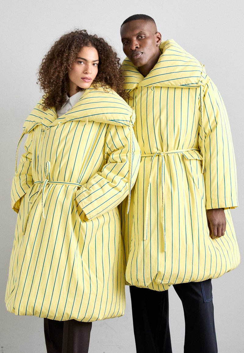 Yellow puffer coats with thick padding and oversized collars, featuring vertical blue stripes and cinched waists with matching ties.