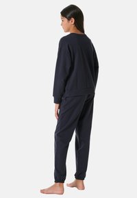 Marinblå sweatshirt och joggers-set i mjuk bomull, med avslappnad passform, elastiska muddar och rundad nederkant.