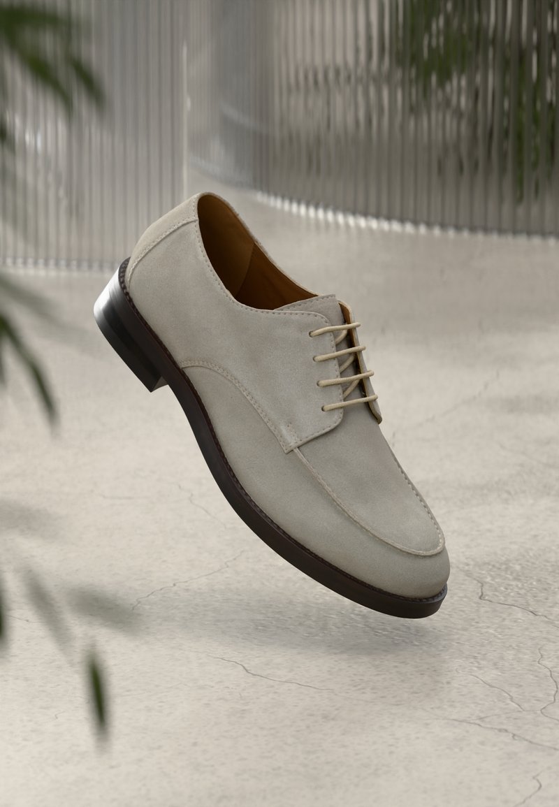 Μπεζ σουέτ παπούτσι με σχέδιο με κορδόνια, στρογγυλή μύτη και σκούρα καφέ σόλα. Διαθέτει λεία υφή και ελάχιστες λεπτομέρειες ραπτικής.