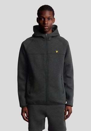 Sweat à capuche zippé gris foncé, avec une capuche, présentant un petit logo jaune sur la poitrine, fabriqué en tissu lisse avec deux poches latérales zippées.