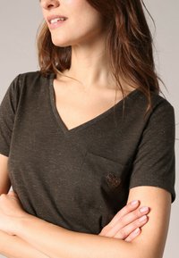 Donkergroene V-hals T-shirt met korte mouwen, voorzien van een hartvormig zakdetail, gemaakt van een gestructureerde stof met een subtiele glans.