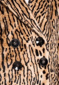 Abrigo cruzado en suave tejido de leopardo, con una base naranja-marrón y rayas negras, y botones circulares negros como cierres.