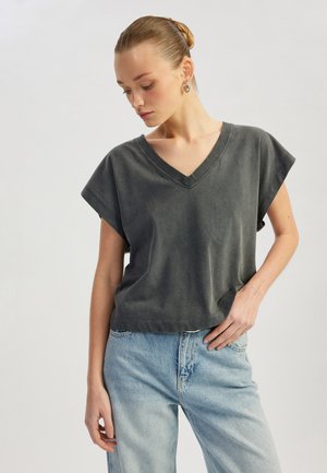 Dunkelgraues V-Ausschnitt-T-Shirt mit kurzen Ärmeln, aus мягкой Stoff. Kombiniert mit hellblauen, locker sitzenden Jeans. Glatte Textur, lässiger Stil.