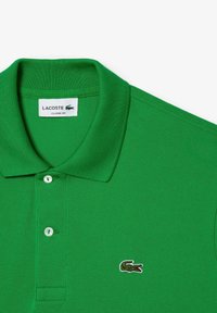 Polo vert en tissu texturé, avec une coupe classique, un col côtelé, trois boutons et un petit logo de crocodile brodé.