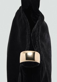 Crni baršunasti torbica s glatkim zlatnim metalnim akcentom. Torbica ima mekanu teksturu i dizajn otvorenog vrha.