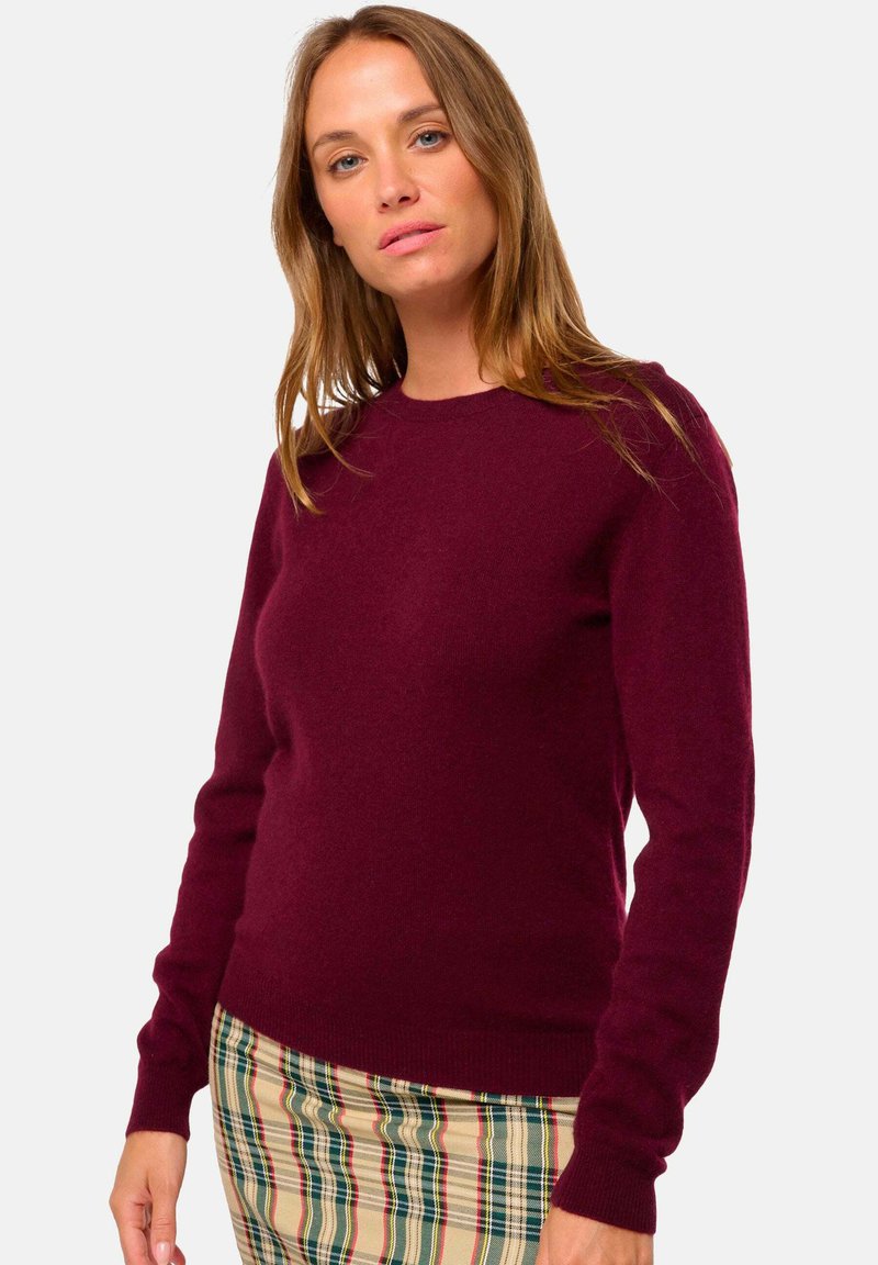 Bordeauxfarbener Wollpullover mit Rundhalsausschnitt und langen Ärmeln, kombiniert mit einem karierten Rock in Creme-, Grün- und Rottönen.