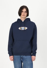 Hoodie bleu marine avec une poche kangourou, un capuchon à cordon, et un logo géométrique en jaune et bleu sur la poitrine. Tissu en coton doux.